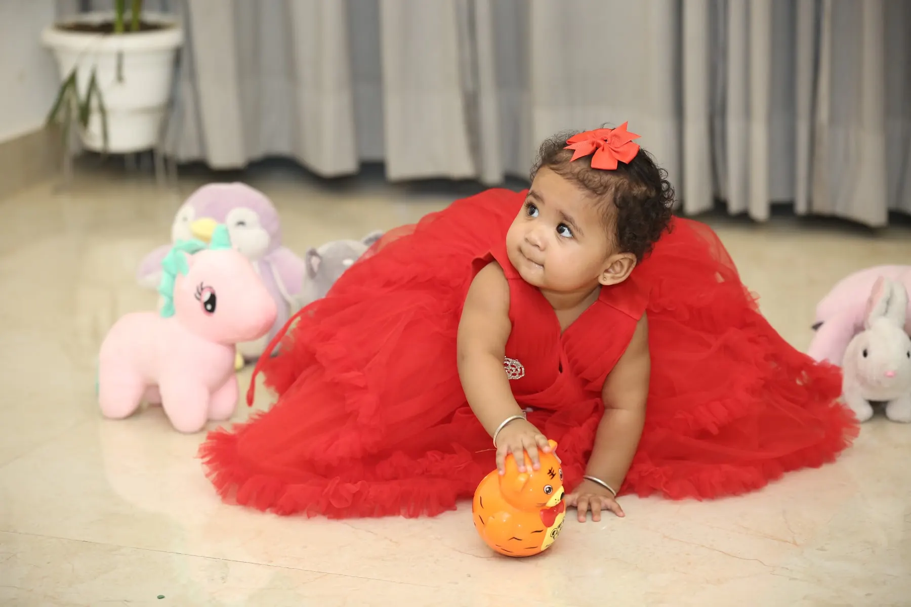 First-birthday portrait of a baby in a red dress